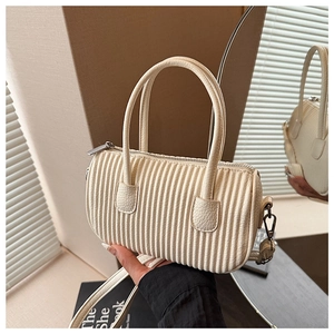 Close-up of pleated cream cylinder bag showing leather texture and silver hardware details