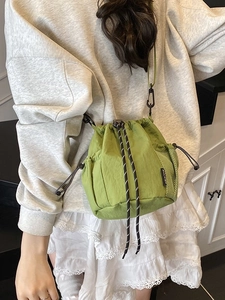 Minimalist light green drawstring bucket bag with mesh pockets and black rope accents