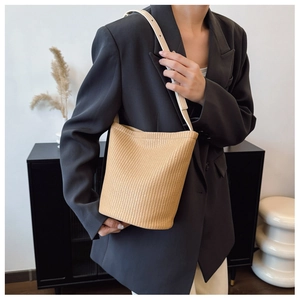 Detail of beige woven bucket bag showing fine straw texture and adjustable leather strap