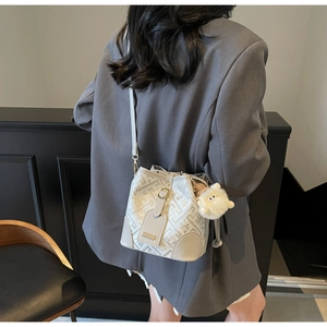 On-model shot showing the size and styling of the patterned bucket bag with plush charm