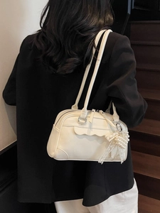 Chic white leather shoulder bag with pearl bow charm worn by model on stairs