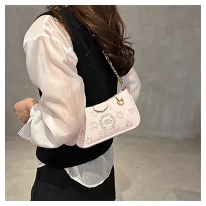 Detail of pink underarm bag featuring red cartoon zodiac prints and golden chain strap