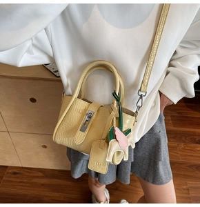 Detailed close-up of yellow crocodile texture handbag with a decorative leather pony charm