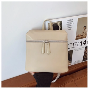 Detailed close-up of cream PU leather backpack with silver dual zippers and top handle
