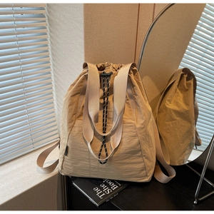 Detail of khaki drawstring bucket bag in pleated nylon with dual handles and straps