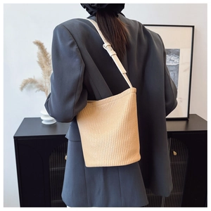 Detail der minimalistischen beige geflochtenen Beuteltasche mit Lederriemen zum Blazer