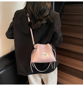 Detail view of light pink bucket bag with drawstring closure and silver chain on model