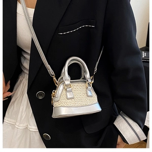 Detail der Mini-Muscheltasche mit silbernem Metallrand und beigem Webmuster am Model