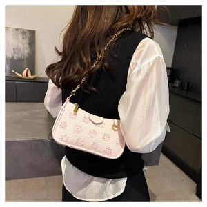 Close-up of pink underarm bag with cartoon prints and a sleek gold metal chain strap