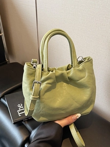 Minimalist avocado green bucket bag with ruched leather and adjustable shoulder strap