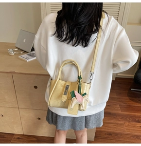 Detail of yellow crocodile pattern handbag with a cute pegasus charm and shoulder strap