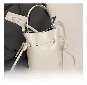 Detail of white glossy bucket bag with drawstring closure and silver metal eyelets