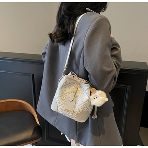 Detail of grey bucket bag with floral embroidery and white plush lamb charm on a model