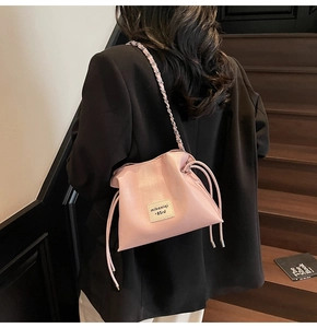 Detail view of pink drawstring bucket bag with silver chain strap and side tassels