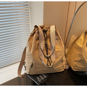 Detail view of khaki nylon drawstring backpack with brand label and woven shoulder strap