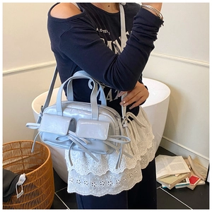 Détail du sac bowling en cuir verni bleu clair avec nœuds et poches frontales