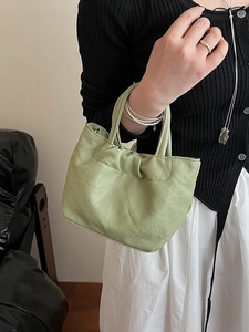 Minimalist pistachio green ruched leather bucket bag with cylindrical top handle design