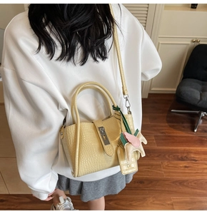 Detail of yellow crocodile pattern mini bag featuring a decorative horse charm and strap