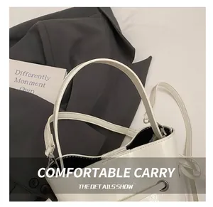 Détail du sac seau blanc en cuir brillant avec large poignée et accents d'œillets
