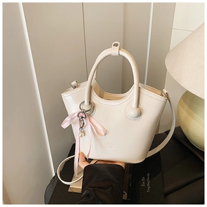 Détail d'un sac seau blanc crème avec texture cuir lisse et pendentif en perles