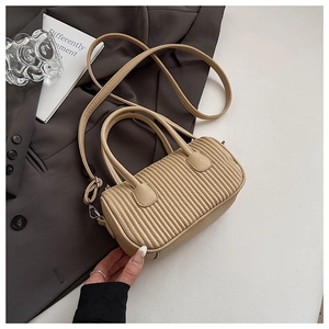 Detailed close-up of the pleated cylindrical beige shoulder bag with silver hardware