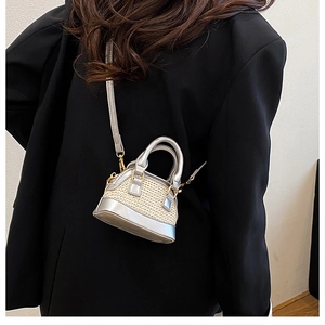 Modell mit kleiner gewebter Muscheltasche in Creme mit silbernen Akzenten und Gold