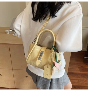 Detail of light yellow crocodile pattern handbag featuring a pink pegasus charm and hardware