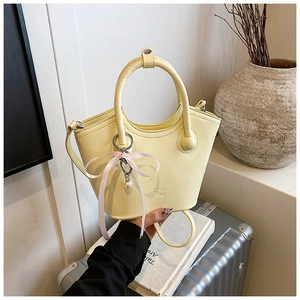 Détail du sac seau jaune pâle avec poignée ronde et breloque ruban perle coeur