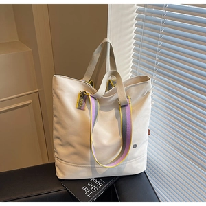 Detail of canvas tote bag with multi-color striped straps and CIAO webbing detail