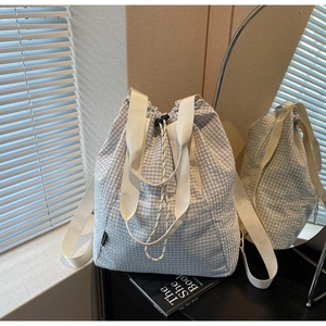 Detail view of light blue checkered drawstring backpack showing quilted nylon fabric texture