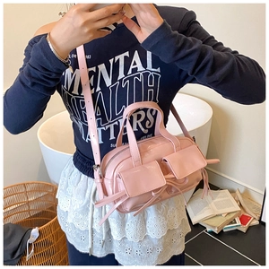 Vue détaillée du sac à main rose brillant avec nœuds décoratifs et bandoulière