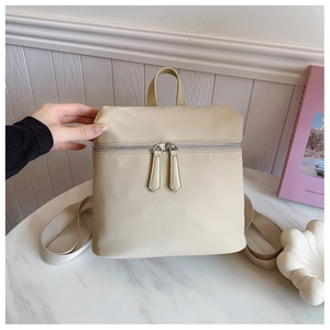 Close-up of minimalist cream white backpack with silver zippers on a marble surface