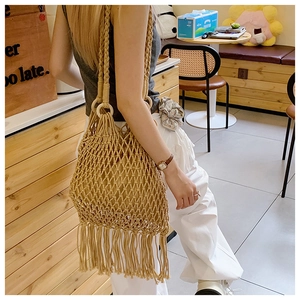Détail du sac à bandoulière en maille tissée avec longues franges et anneaux en bois