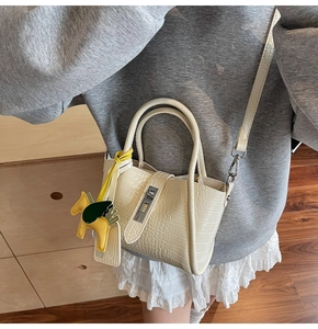 Detail of cream crocodile embossed bucket bag with silver twist lock and Pegasus charm