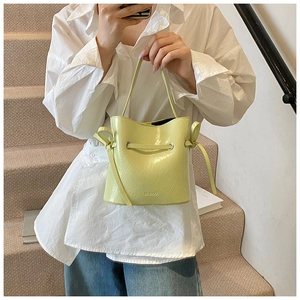 Detailed macro view of yellow bucket bag featuring glossy wrinkled leather texture