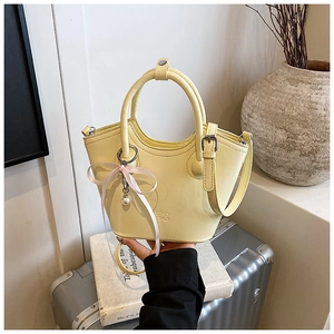Détail d'un sac à main jaune crème en similicuir avec charm perle et nœud en ruban rose