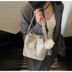 Detail of light grey bucket bag with geometric patterns and plush eye charm accessory