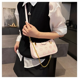 Détail d'un sac bandoulière rose avec texture litchi et chaîne dorée élégante