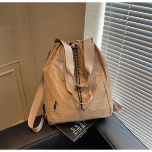 Detail of khaki drawstring backpack featuring pleated texture and wide webbing handle