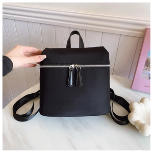 Close-up of black nylon backpack featuring leather handle and wide adjustable straps