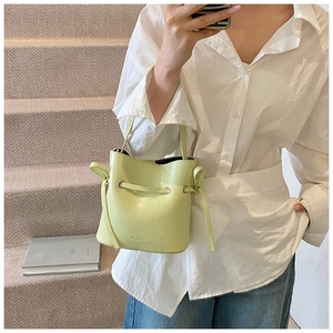 Detail of light green bucket bag with crinkled texture and Muduo brand embossing