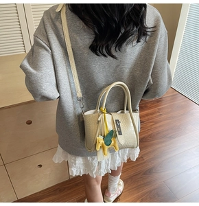 Detail of beige crocodile pattern handbag with silver twist lock and yellow pegasus charm