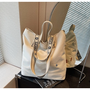 Detail of wide SJCHAO branded straps and reinforced seams on this cream canvas tote bag