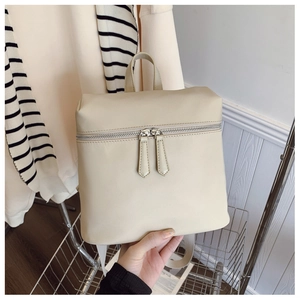 Detail of beige faux leather backpack showing dual horizontal zippers and fine texture