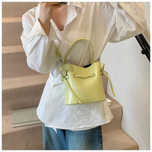 Detail shot of a lime green bucket bag featuring lychee texture and drawstring accents