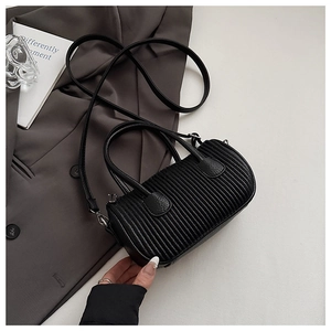 Macro detail of black pleated cylinder bag texture and silver metal hardware accents