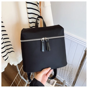 Detail of minimalist black nylon backpack with silver zippers and water-resistant fabric