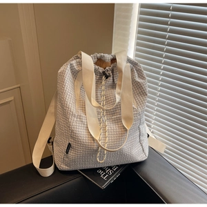 Detail of blue and white checkered drawstring bucket bag with textured rope closure