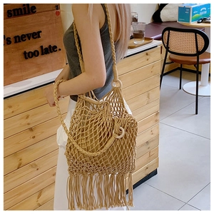Détail du sac à bandoulière tissé à la main avec de longues franges et des anneaux en bois
