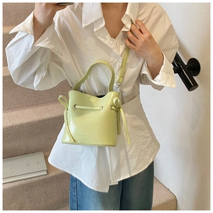 Light green matte leather bucket bag with embossed logo shown on a fashion model